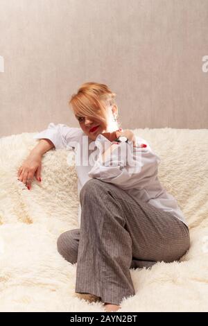 Porträt einer attraktiven Frau mittleren Alters. Hausgemachtes Porträt auf der Couch, blond im mittleren Alter. Stockfoto