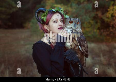 Frauenschaman mit Hörnern hält eine Eule in ihren Händen. Stockfoto