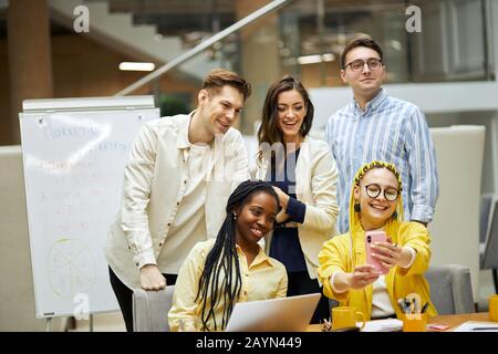 Fröhliche junge Männer und Frauen plaudern, ein Gespräch mit ihrem im Ausland ruhenden Freund führen, Videogespräche führen, anrufen. Kollegen, die einen Videoanruf tätigen Stockfoto