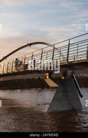 Wetter in Großbritannien. Pendler gehen über die Millennium Bridge am überfluteten Fluss Ouse in York vorbei. Stockfoto