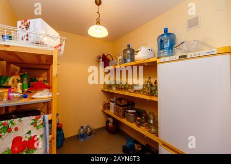 Lagerraum im Cottage. Lagerung. Regale mit zahlreichen Dosen und Flaschen, Kühlschrank. Stockfoto