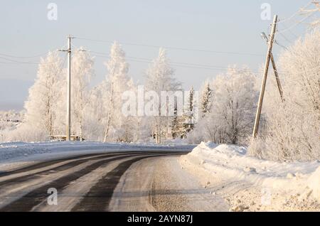 Schöne Straße durch den Winterwald. Frostige Reise Stockfoto