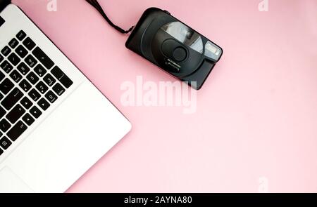 Schwarz-weiße Laptop-Tastatur, Filmkamera, auf pinkfarbenem Hintergrund. Kopierbereich. Flaches Lay. Draufsicht. Stockfoto