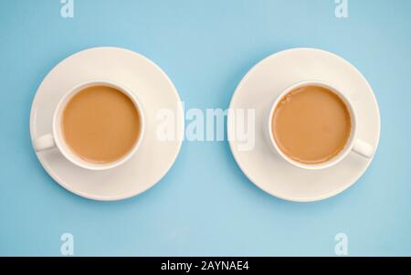 Zwei weiße Tassen Kaffee mit Milch, hellblauer Hintergrund, Draufsicht. Americano. Kopierbereich Stockfoto