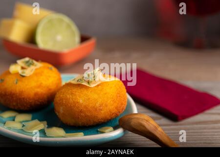 Hausgemachte Kroketten, gefüllt mit Käse mit Zitrone und einem Glas Rotwein. Stockfoto