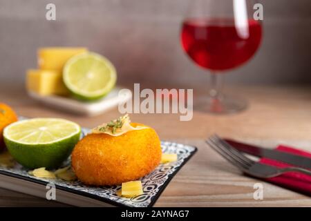 Hausgemachte Kroketten, gefüllt mit Käse mit Zitrone und einem Glas Rotwein. Stockfoto