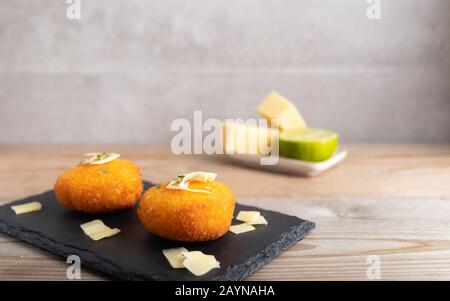 Hausgemachte Kroketten, gefüllt mit Käse mit Zitrone und einem Glas Rotwein. Stockfoto