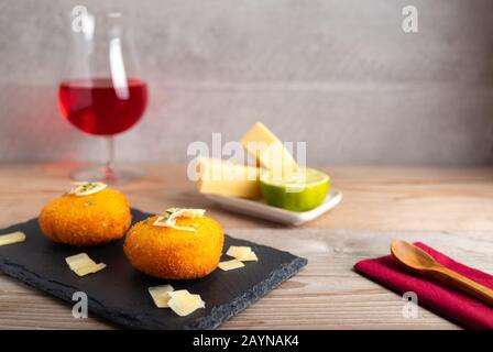 Hausgemachte Kroketten, gefüllt mit Käse mit Zitrone und einem Glas Rotwein. Stockfoto