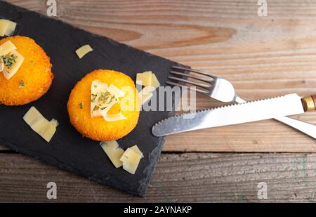 Hausgemachte Kroketten, gefüllt mit Käse mit Zitrone und einem Glas Rotwein. Stockfoto