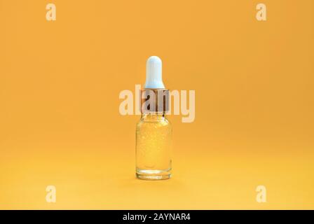 Kosmetiköl, Serum in einer transparenten Flasche mit einem Tropfflaschen auf orangefarbenem Hintergrund. Platz für Text Stockfoto