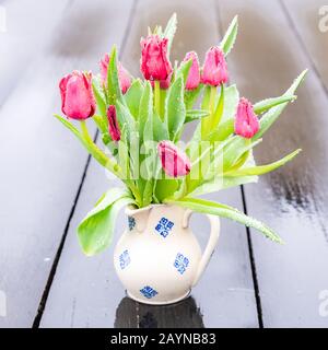 Blumenstrauß aus roten Tulpen in einer Vintage-Vase im Regen, Stillleben Stockfoto