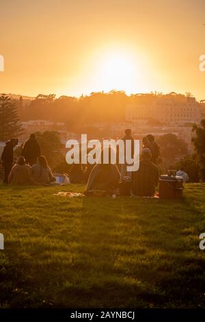 Paare beobachten den Sonnenuntergang vom Alamo Square Park in San Francisco, Kalifornien. Stockfoto