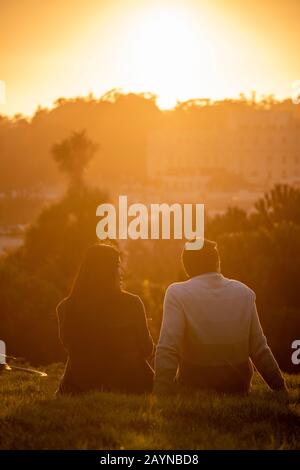 Paare beobachten den Sonnenuntergang vom Alamo Square Park in San Francisco, Kalifornien. Stockfoto