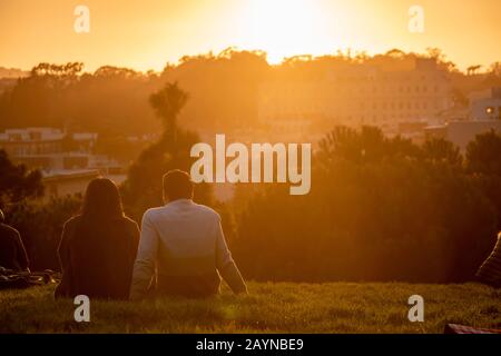 Paare beobachten den Sonnenuntergang vom Alamo Square Park in San Francisco, Kalifornien. Stockfoto