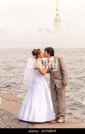 Neuvermählte küssen sich am Ufer des Flusses Newa, Sankt Petersburg, Russland Stockfoto