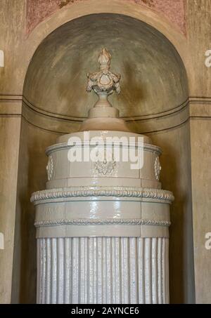 Europäischer alter Ofen mit Keramikplatte aus Majolika. Kaminofen aus Keramikholz Stockfoto