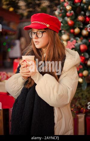 Warmherzig Gekleidete Frau Vor Dem Dekorierten Weihnachtsbaum. Stockfoto