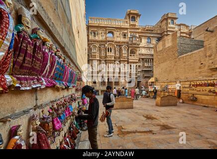 Marionetten an einer Wand als Souvenir mit Patwon Ki Haveli hinter, Jaisalmer, Rajasthan, Indien Stockfoto