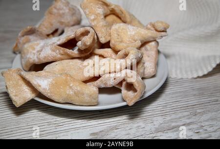 Süßigkeiten / Dessert / Kuchen namens Faworki / Chrust in Polnisch traditionell am Fat Donnerstag serviert, Teller auf Holztisch aus der Nähe. Stockfoto