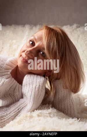 Eine schöne, elegante, Erwachsene Frau liegt auf einem Sofa. Nahaufnahme des Gesichts einer gepfeilten Blondine mittleren Alters. Stockfoto