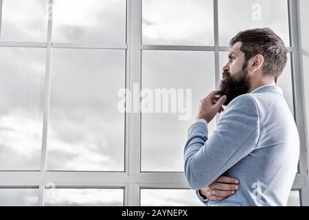 Richtige Entscheidung. Hochzeitmorgen Konzept. Hochzeitstag. Besen gebärdeter Flusspferd reifer Mann tragen hellblauen Tuxedo und Krawatte. Mann steht nervös über Hochzeit am Fenster. Lebensentscheidungen und -Erwartungen. Stockfoto