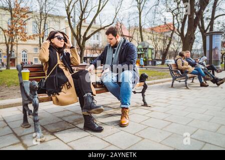 Junge erwachsene Paare essen fast food auf der Werkbank von City Park Stockfoto