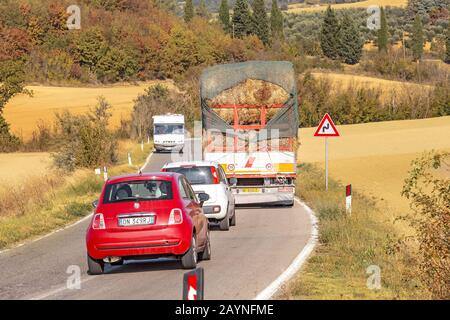 18. OKTOBER 2018, MONTEPULCIANO, ITALIEN: Auto überholt LKW mit Heustapeln auf der Landstraße. Dangreous Unfall und Stau Stockfoto