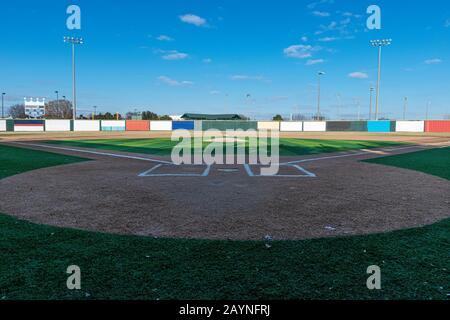 Blick auf ein Baseballfeld mit Kunstrasen, wie es von hinter dem Homeplatte aus zu sehen ist, und Blick über den Hügel des Pitchers zum Außenfeld. Stockfoto