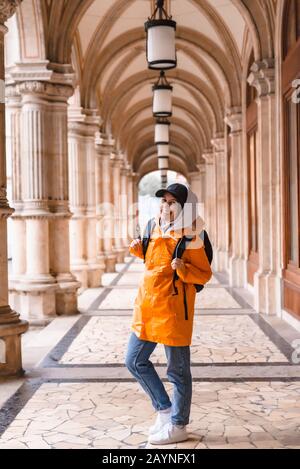 Frau Touristen zu Fuß mit Rucksack im gelben Regenmantel Stadt Tourismus Stockfoto