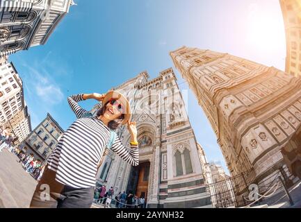 Glückliche asiatikanerin mit erhobenen Händen am alten Stadtplatz von Florenz in der Nähe der Kathedrale Santa Maria Del Fiore. Reisen in Italien Konzept Stockfoto