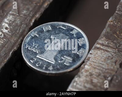 Draufsicht über die eine Yuan-Münze in einem Metall-Schraubstock. Währung und Wirtschaft unter dem Ansturm, das Konzept der finanziellen Probleme und der Krise Stockfoto