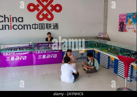 Kinder, die Kartenspiel in einem Handyladen in einem neuen Teil der Stadt Fengdu spielen, das für Menschen gebaut wurde, die aufgrund des c umgesiedelt werden mussten Stockfoto