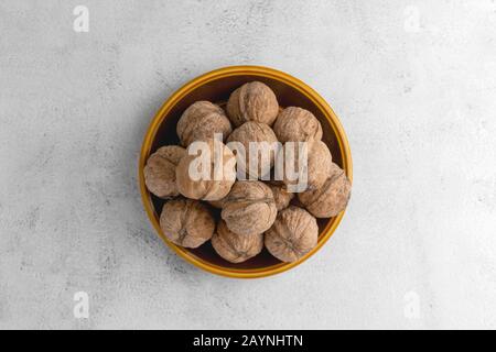 Walnüsse in runder Platte auf hell strukturierter Oberfläche. Gesunde Nüsse, gesunde Lebensmittel. Stockfoto