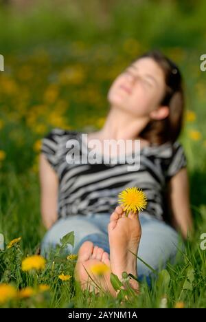 Junge Frau geniefelt die Sonne auf einer Wiese Stockfoto