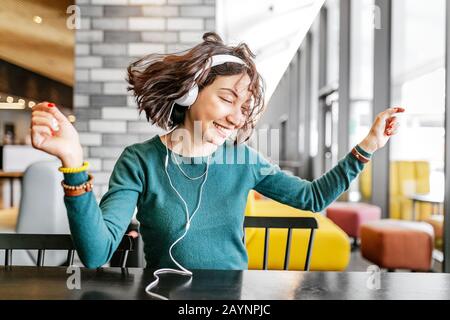 Junge glückliche Frau mit Kopfhörern, die ihr Lieblingslied über Wi-Fi Internet hört Stockfoto