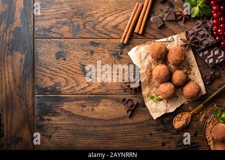 Hausgemachte Schokoladentrüffel mit Gewürzen auf Holztisch mit Kopierraum, Draufsicht. Dunkles Schokoaltbonbon Stockfoto
