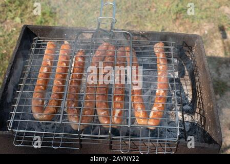 Wurst im Grill auf dem Spiel. Ein Picknick in der Natur bei Sonnenuntergang. Stockfoto