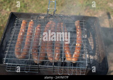 Wurst im Grill auf dem Spiel. Ein Picknick in der Natur bei Sonnenuntergang. Stockfoto