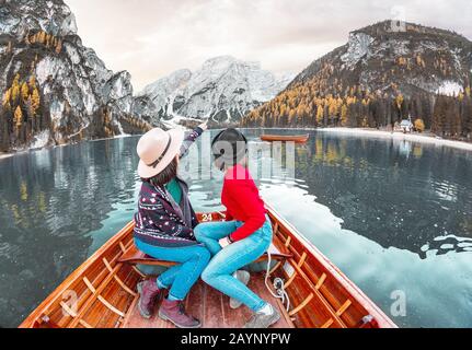 Zwei glückliche Frauen mit Freunden auf der Boot- oder Kanufahrt auf dem lago Di Braies See in den italienischen Alpen der Dolinen Stockfoto