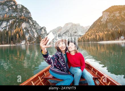 Zwei glückliche Freundinnen machen selfie Foto auf dem Boot oder Kanufahrt auf dem lago Di Braies See in den italienischen Dolmen Alpen Stockfoto