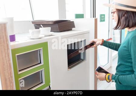 Frau bringt Müll und Reste des Fastfood-Restaurants in die Mülltonne Stockfoto