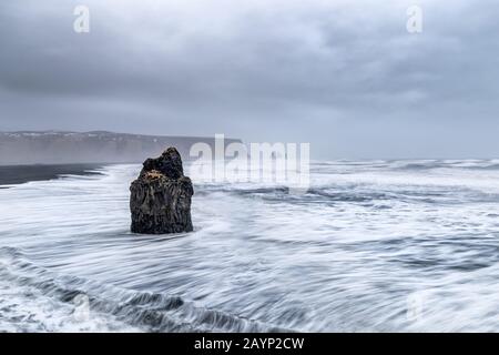 Arnardrangur, oder Eagle Rock, in Dyrholaey, Südisland. Das Gestein wird so genannt, weil Adler es früher nisten. Zusammensetzung der Langzeitbelichtung mit R Stockfoto