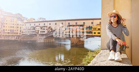 Glückliche Reisende asiaten auf einem Urlaub in Florenz bewundern die Aussicht auf die berühmte Sehenswürdigkeit Ponte Vecchio während der Reise in Italien, Europa Stockfoto