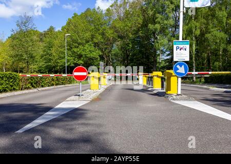 Ein Porträt einer Straße, die von einer Absperrbar mit einigen Verkehrsschildern vor sich geschlossen wurde. Das automatische Gate-System bietet zusätzliche Sicherheit durch u Stockfoto