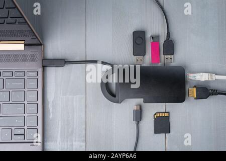 USB-Adapter Typ C oder Hub, der mit verschiedenen Zubehörteilen an den Laptop angeschlossen ist - Pendreifen, hdmi, ethernet, Speicherkarte, Kabel. Flacher Lay Draufsicht. Stockfoto