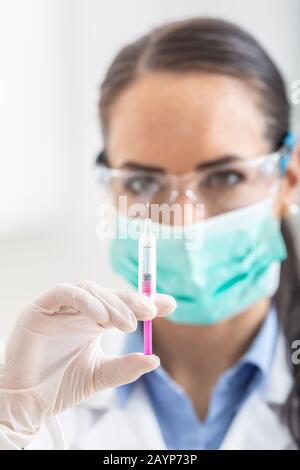 Ärztin arbeiten mit Nadel und ampulle von Medizin. Ein Wissenschaftler in sterilen Kleidung ist ein Impfstoff, der Droge. Stockfoto