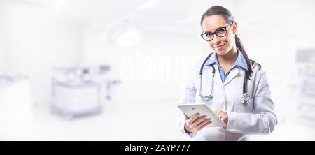 Ärztin hält tablett-pc vor dem OP-Raum. Stockfoto