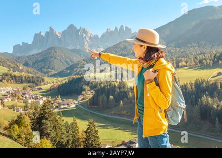 Eine glückliche asiatin, die während der Herbstsaison eine großartige Aussicht auf das Tal der Fünen in den Alpen der Alpen der Alpen in Italien genießt Stockfoto