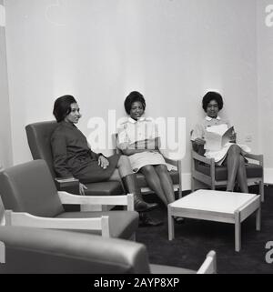 In den 1960er Jahren saßen historische drei Krankenschwestern in ihrem Gemeinschaftsraum auf niedrigen Sesseln, die typisch für die Epoche sind, im Brook General Hospital, Southeast London, England, Großbritannien. Stockfoto