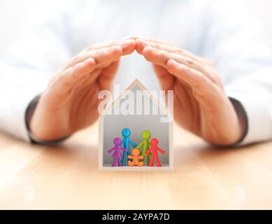 Bunte Familienfigürchen in Holzhaus mit Handschutz Stockfoto